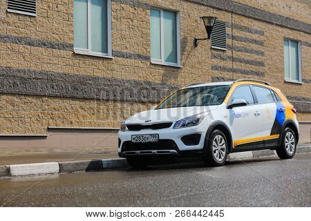 MOSCOW - MAY 1, 2018: Wet white Kia car of Moscow carsharing company Yandex Drive at sunny street after rain, carsharing is system of short-term car rental