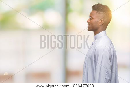 Young arabic african man wearing traditional djellaba over isolated background looking to side, relax profile pose with natural face with confident smile.