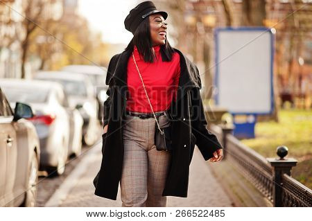 African American Fashion Girl In Coat And Newsboy Cap Posed At Street.