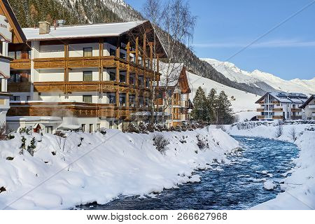 Ischgl, Austria - December 29, 2017: Small Mountain Stream In Tyrol Alps. Wooden House Near Mountain