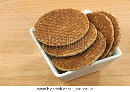 Holandská vafle v bílé misce nazývá stroopwafel na dřevěné pozadí