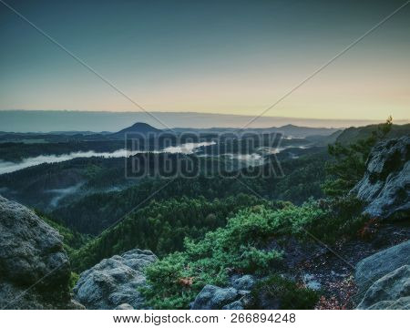 Peak Of Sandstone Rock With View Into Colorful Mist In Morning Valley. Blue Eyllow Daybreak Sun Hidd