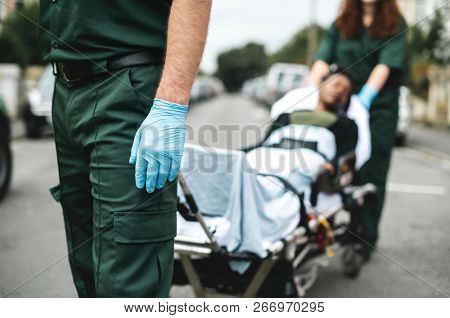 Paramedics moving a patient on a stretcher to an ambulance