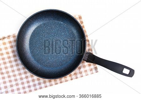 Black Frying Pan On Kitchen Towel Isolated On White Background