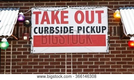 A Restaraunt Has A Take Out Only And Curbside Pick Up Sign Posted On The Brick Wall Of Their Buildin