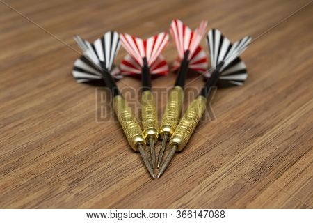 Darts With Color Plumage Lie On A Wooden Table. Close-up