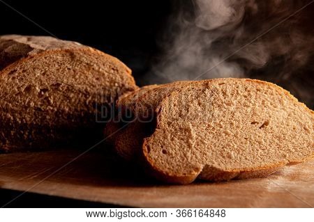 Baked Bread Cut Into Pieces On A Black Background. Hot Bread