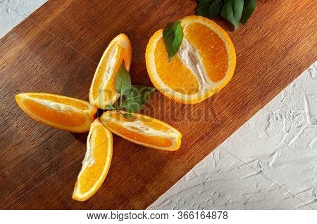 Whole And Slices Of Oranges With Green Leaves Lie On A Wooden Board On A White Background. Bright Or