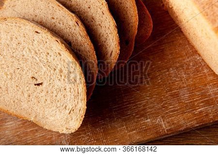 Baked Bread Cut Into Pieces On The Wooden Board