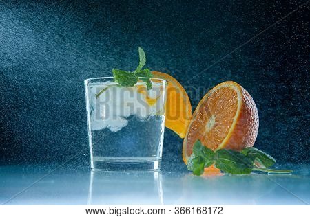 Fresh Lemonade With Mint, Orange And Ice In A Glass Jar On A Dark Blue Background. Splashing Water S