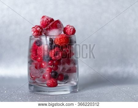 Fresh Strawberry, Raspberry With Ice In The Glass On The Shining Background
