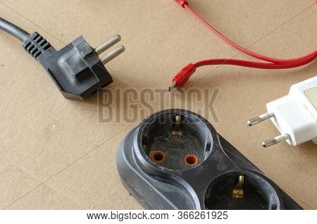 Black Power Strip With Disconnected Electricity Consumers On A Beige Background. A Developer With Di