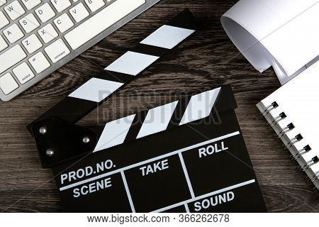Black Movie Clapper With Keyboard And Script Sheets On A Wooden Table Top View