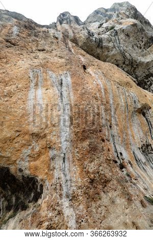 Limestone Cliff Wall Overlooking People And Some Veins Of Ferrous Material