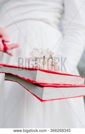 Girls Holds Book Of Red Color In A Hand On A Book Of Flowers Flowering Spring Foliage White Red