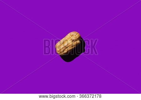 Creative Art With Yellow Eclair On Purple Background. Flat Lay