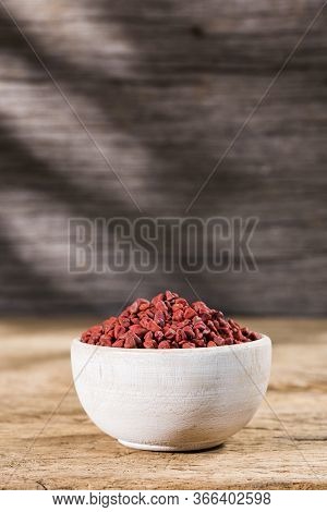 Annatto Seeds In Bowl On Wooden Background