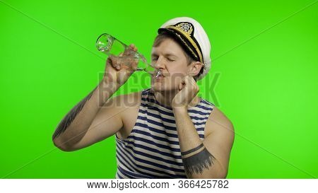 Young Drunk Muscular Sailor Man Drinks Vodka From Bottle. Seaman Guy Smiling In Sailors Vest. Stripe