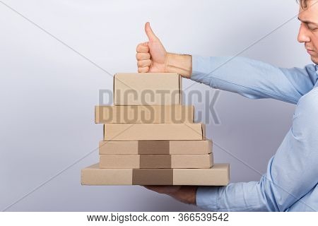 Man Holding Cardboard Box And Shows Gesture Well Done. Good Service Delivery Concept.