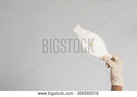 Closeup Of A Hand With Glove Holding   A Ffp3 Class Mask On Gray Background. Space For Text