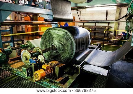 African Factory Worker Checking A Roll Of Rubber On A Machine In A Conveyor Belt Factory