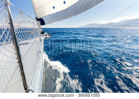 Sailing with fresh speed wind. A view from the yacht's deck to the bow and sails. Sail boat with set up sails gliding in open sea. Greece, Europe