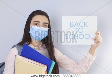 High School Girl With Mask On Her Showing Back To School Message. Student Girl Ready For School Duri