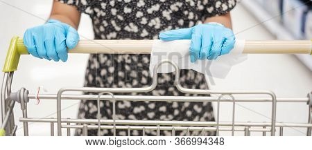Asian Woman Wearing Nitrile Gloves And Cleaning Surface Of Shopping Cart By Wet Wipe In Supermarket 