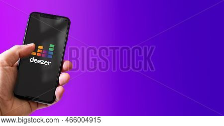 Paris - France - March 15, 2022 : Hand Holding Iphone Smartphone With Deezer Logo. Horizontal Banner