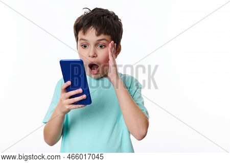 Shocked Caucasian Teenage Boy Using Mobile Phone, Reading News, Expressing Shock, Surprise, Stupefac