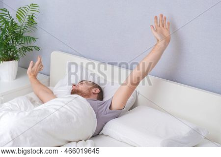 A Happy Man Wakes Up In The Morning After Sleeping. A Man Is Awake After Sleeping. Lazy Awakening Of