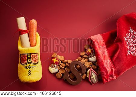Saint Nicholas - Sinterklaas Day With Shoe, Carrot And Traditional Sweets On Red Background