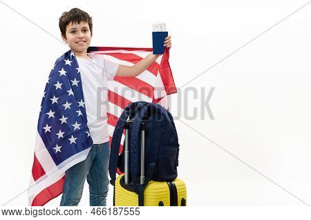 Happy Preteen Boy In White T-shirt And Blue Jeans, Holds Usa Flag And Boarding Pass, Smiles At Camer
