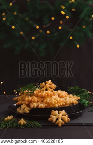 Cookies Brushwood In The Form Of Snowflakes Lie In A Slide On A Black Plate In A Christmas Decoratio