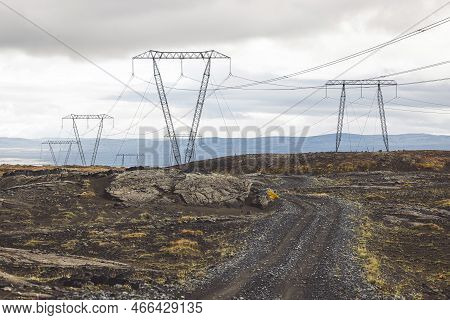 High Voltage Electrical Cables On Poles, With A Backdrop Of A Cloudy Sky