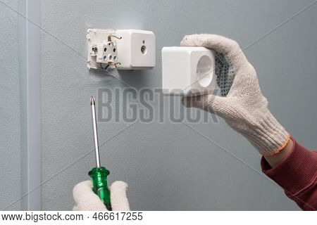 Man Repairing An Electrical Outlet With A Screwdriver. Man Repairing A Socket. Man Holding A Screwdr