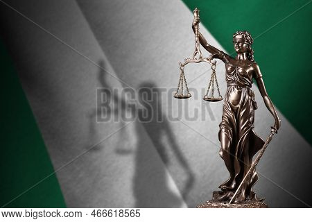 Nigeria Flag With Statue Of Lady Justice And Judicial Scales In Dark Room. Concept Of Judgement And 