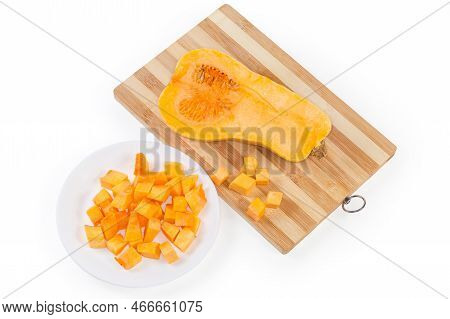 Diced Slices Of The Butternut Squash On The Dish, Half Of The Same Squash Cut Lengthwise On The Wood