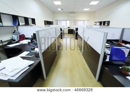 Lugares vazios de trabalho separados por partição com desktops e papéis.