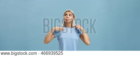 Girl Feeling Discomfort From Heat Standing Over Blue Background In Fug Breathing Out And Frowning Lo