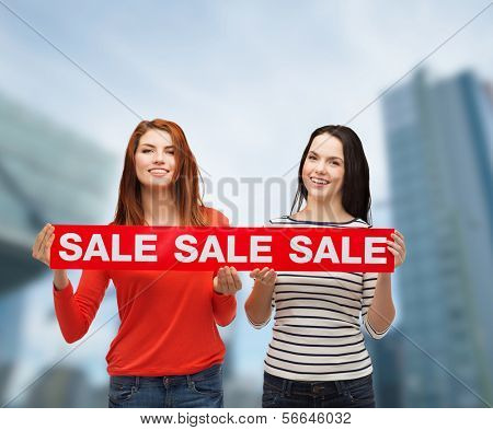 покупки, продажи и дар sconcept - два улыбаясь девочек-подростков с продажей подписать на открытом воздухе