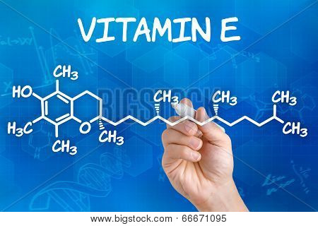 Hand with pen drawing the chemical formula of Vitamin E