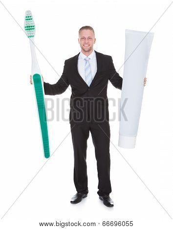 Smiling Business Man Holding A Large Outsized Toothbrush
