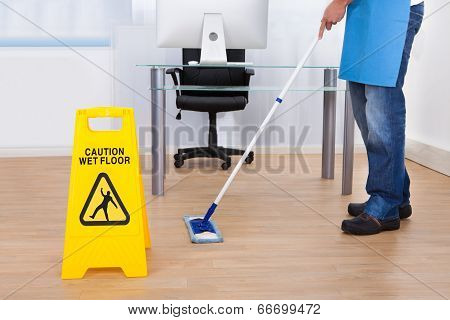 Warning Notice As A Janitor Mops The Floor