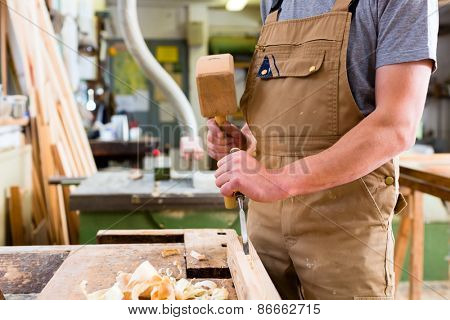 Carpenter with chisel and hammer