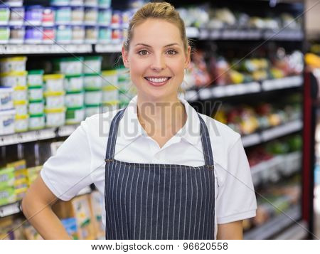 Portrait of a smiling blonde worker with hand on hip in supermarker