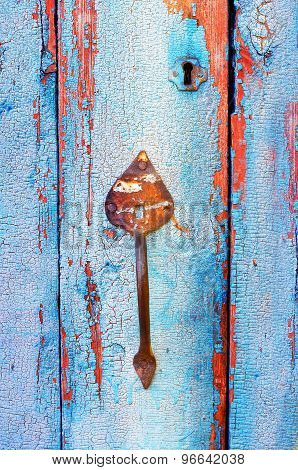 Old tacky blue door with vintage handle and keyhole, wooden texture