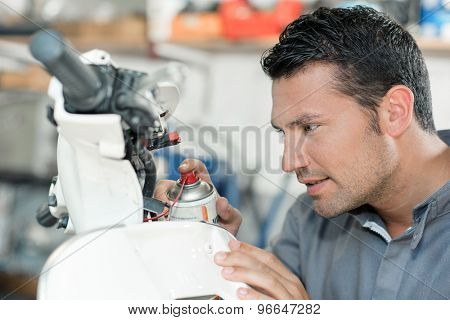 Mechanic spraying lubricant on a scooter