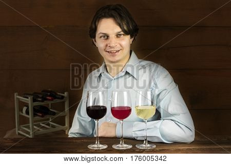 A photo of an enologist tasting wine at a winery, with three glasses in front of him