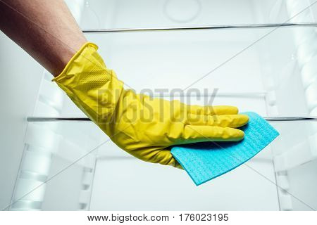 Man's Hand Cleaning White Fridge With Blue Rag